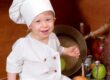 Small boy sitting on a counter wearing a chef's hat